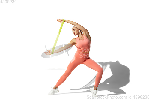 Image of Beautiful young female athlete practicing on white studio background with shadow