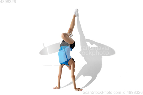 Image of Beautiful young female athlete stretching on white studio background with shadows