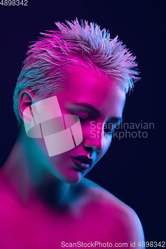 Image of Portrait of female fashion model in neon light on dark studio background.