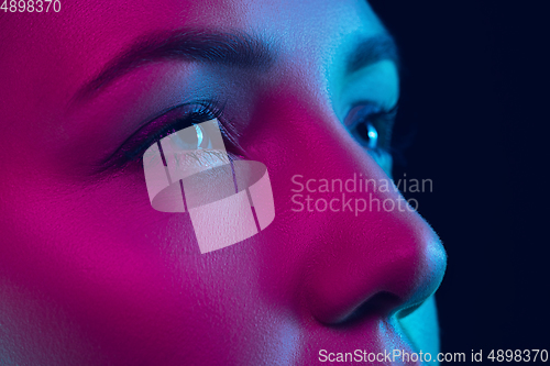 Image of Portrait of female fashion model in neon light on dark studio background.