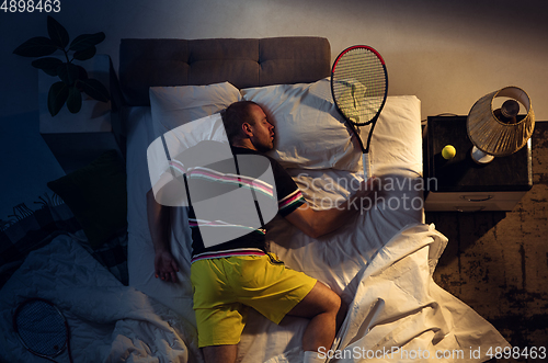 Image of Top view of young professional tennis player sleeping at his bedroom in sportwear with racket