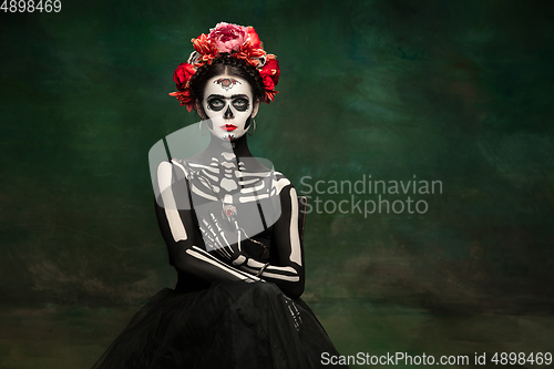 Image of Young girl in the image of Santa Muerte, Saint death or Sugar skull with bright make-up. Portrait isolated on studio background.