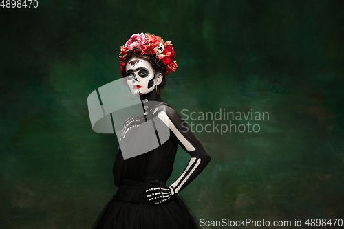 Image of Young girl in the image of Santa Muerte, Saint death or Sugar skull with bright make-up. Portrait isolated on studio background.