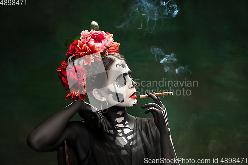 Image of Young girl in the image of Santa Muerte, Saint death or Sugar skull with bright make-up. Portrait isolated on studio background.