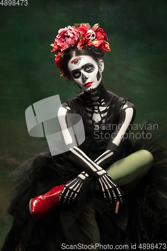 Image of Young girl in the image of Santa Muerte, Saint death or Sugar skull with bright make-up. Portrait isolated on studio background.