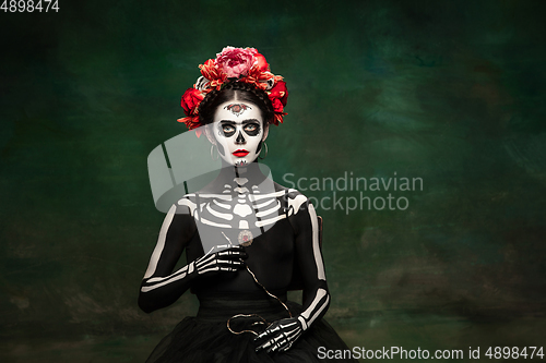 Image of Young girl in the image of Santa Muerte, Saint death or Sugar skull with bright make-up. Portrait isolated on studio background.