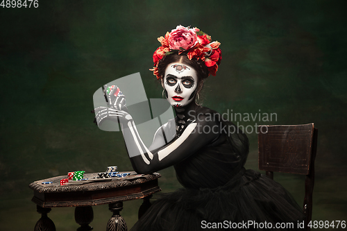 Image of Young girl in the image of Santa Muerte, Saint death or Sugar skull with bright make-up. Portrait isolated on studio background.