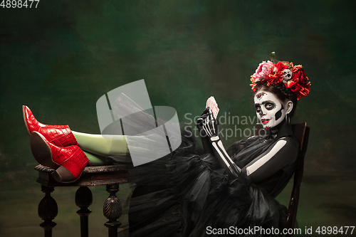 Image of Young girl in the image of Santa Muerte, Saint death or Sugar skull with bright make-up. Portrait isolated on studio background.