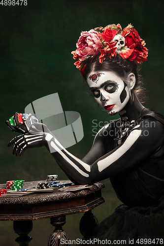 Image of Young girl in the image of Santa Muerte, Saint death or Sugar skull with bright make-up. Portrait isolated on studio background.