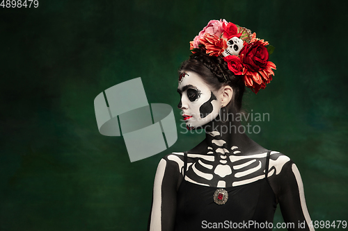 Image of Young girl in the image of Santa Muerte, Saint death or Sugar skull with bright make-up. Portrait isolated on studio background.