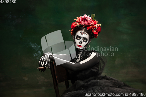 Image of Young girl in the image of Santa Muerte, Saint death or Sugar skull with bright make-up. Portrait isolated on studio background.