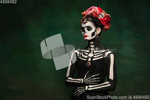 Image of Young girl in the image of Santa Muerte, Saint death or Sugar skull with bright make-up. Portrait isolated on studio background.