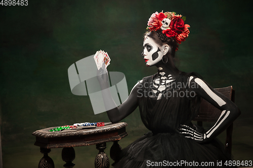 Image of Young girl in the image of Santa Muerte, Saint death or Sugar skull with bright make-up. Portrait isolated on studio background.