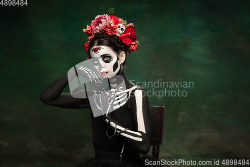 Image of Young girl in the image of Santa Muerte, Saint death or Sugar skull with bright make-up. Portrait isolated on studio background.