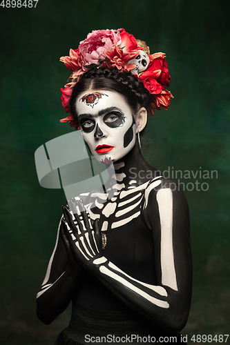 Image of Young girl in the image of Santa Muerte, Saint death or Sugar skull with bright make-up. Portrait isolated on studio background.