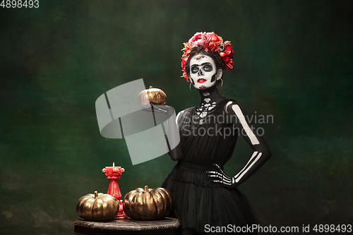 Image of Young girl in the image of Santa Muerte, Saint death or Sugar skull with bright make-up. Portrait isolated on studio background.