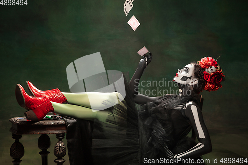 Image of Young girl in the image of Santa Muerte, Saint death or Sugar skull with bright make-up. Portrait isolated on studio background.