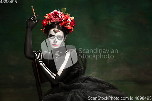 Image of Young girl in the image of Santa Muerte, Saint death or Sugar skull with bright make-up. Portrait isolated on studio background.