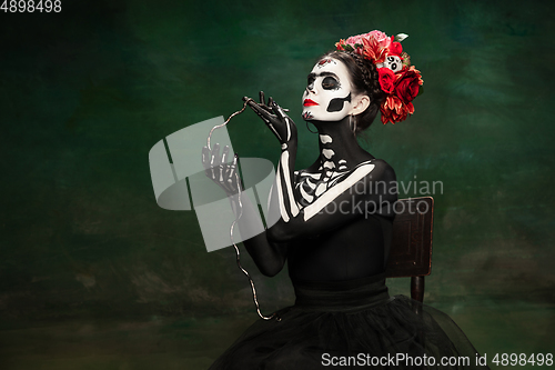 Image of Young girl in the image of Santa Muerte, Saint death or Sugar skull with bright make-up. Portrait isolated on studio background.