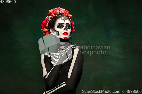 Image of Young girl in the image of Santa Muerte, Saint death or Sugar skull with bright make-up. Portrait isolated on studio background.