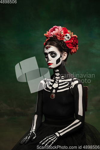 Image of Young girl in the image of Santa Muerte, Saint death or Sugar skull with bright make-up. Portrait isolated on studio background.