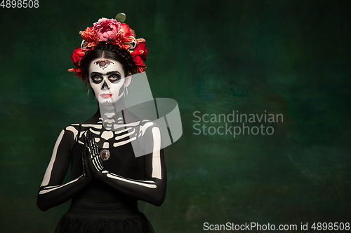 Image of Young girl in the image of Santa Muerte, Saint death or Sugar skull with bright make-up. Portrait isolated on studio background.