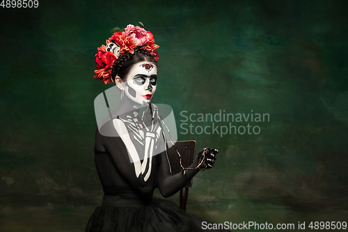 Image of Young girl in the image of Santa Muerte, Saint death or Sugar skull with bright make-up. Portrait isolated on studio background.