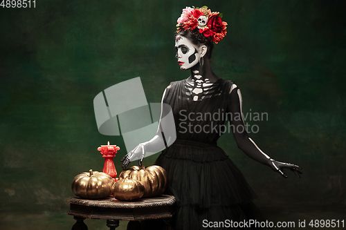 Image of Young girl in the image of Santa Muerte, Saint death or Sugar skull with bright make-up. Portrait isolated on studio background.