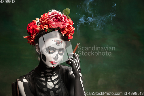 Image of Young girl in the image of Santa Muerte, Saint death or Sugar skull with bright make-up. Portrait isolated on studio background.