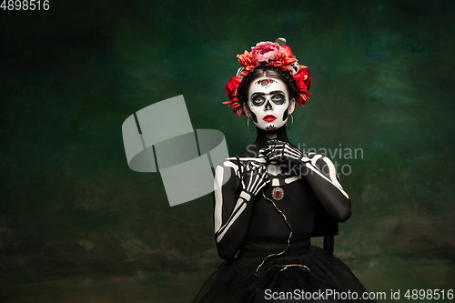 Image of Young girl in the image of Santa Muerte, Saint death or Sugar skull with bright make-up. Portrait isolated on studio background.