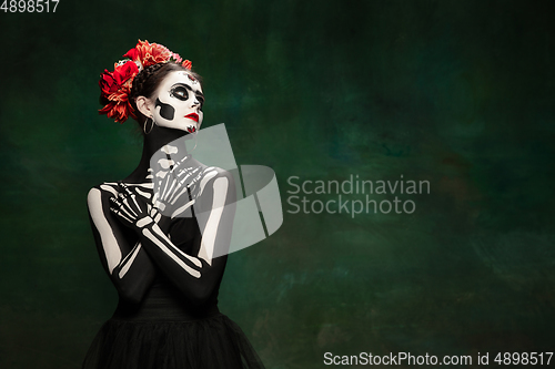 Image of Young girl in the image of Santa Muerte, Saint death or Sugar skull with bright make-up. Portrait isolated on studio background.