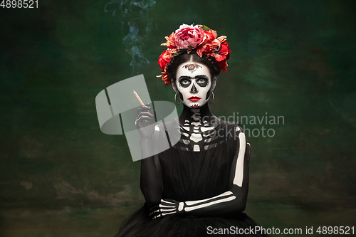 Image of Young girl in the image of Santa Muerte, Saint death or Sugar skull with bright make-up. Portrait isolated on studio background.