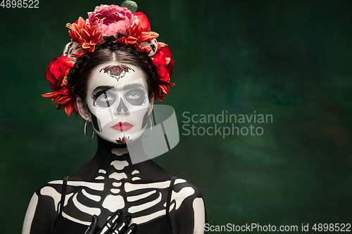 Image of Young girl in the image of Santa Muerte, Saint death or Sugar skull with bright make-up. Portrait isolated on studio background.