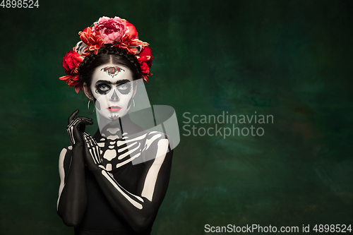 Image of Young girl in the image of Santa Muerte, Saint death or Sugar skull with bright make-up. Portrait isolated on studio background.