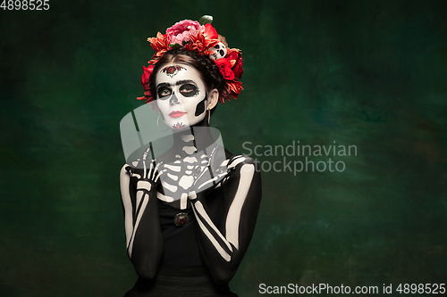 Image of Young girl in the image of Santa Muerte, Saint death or Sugar skull with bright make-up. Portrait isolated on studio background.