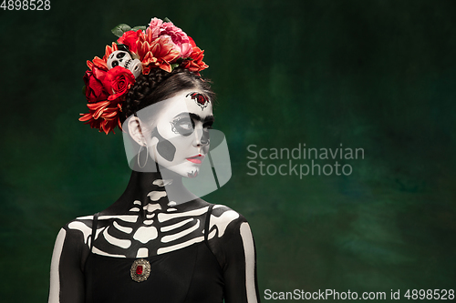 Image of Young girl in the image of Santa Muerte, Saint death or Sugar skull with bright make-up. Portrait isolated on studio background.