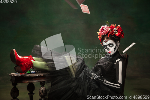 Image of Young girl in the image of Santa Muerte, Saint death or Sugar skull with bright make-up. Portrait isolated on studio background.