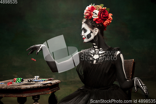 Image of Young girl in the image of Santa Muerte, Saint death or Sugar skull with bright make-up. Portrait isolated on studio background.