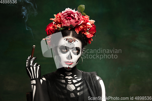 Image of Young girl in the image of Santa Muerte, Saint death or Sugar skull with bright make-up. Portrait isolated on studio background.