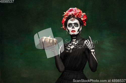 Image of Young girl in the image of Santa Muerte, Saint death or Sugar skull with bright make-up. Portrait isolated on studio background.