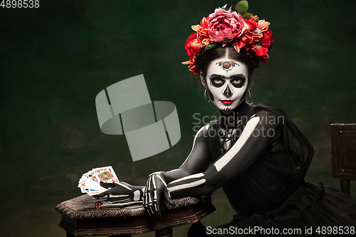 Image of Young girl in the image of Santa Muerte, Saint death or Sugar skull with bright make-up. Portrait isolated on studio background.