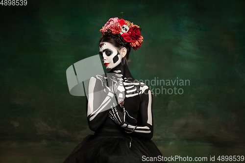 Image of Young girl in the image of Santa Muerte, Saint death or Sugar skull with bright make-up. Portrait isolated on studio background.