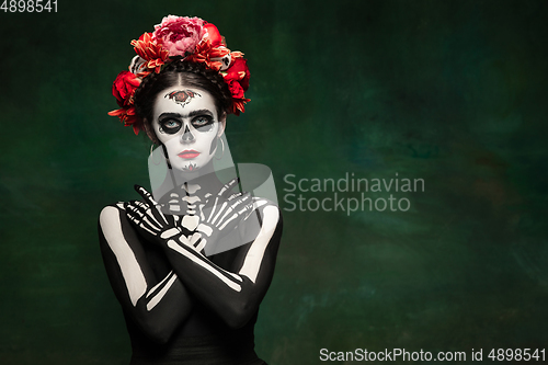 Image of Young girl in the image of Santa Muerte, Saint death or Sugar skull with bright make-up. Portrait isolated on studio background.