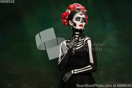 Image of Young girl in the image of Santa Muerte, Saint death or Sugar skull with bright make-up. Portrait isolated on studio background.