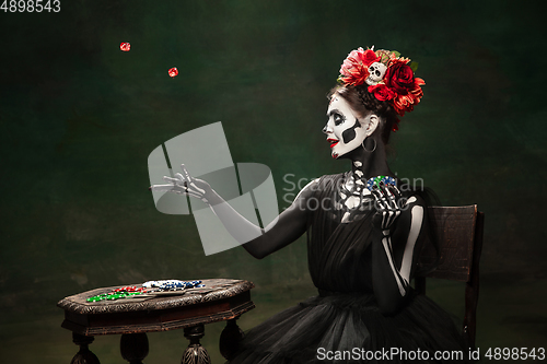 Image of Young girl in the image of Santa Muerte, Saint death or Sugar skull with bright make-up. Portrait isolated on studio background.