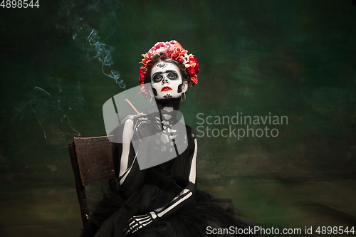 Image of Young girl in the image of Santa Muerte, Saint death or Sugar skull with bright make-up. Portrait isolated on studio background.