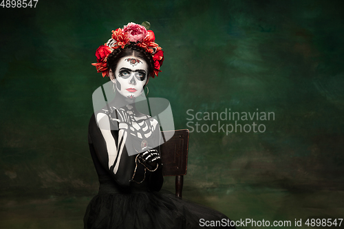 Image of Young girl in the image of Santa Muerte, Saint death or Sugar skull with bright make-up. Portrait isolated on studio background.