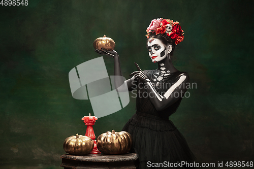 Image of Young girl in the image of Santa Muerte, Saint death or Sugar skull with bright make-up. Portrait isolated on studio background.