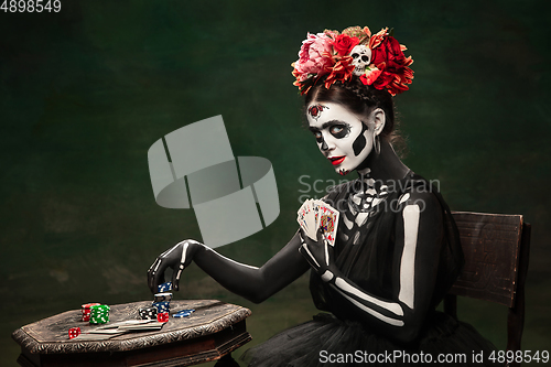 Image of Young girl in the image of Santa Muerte, Saint death or Sugar skull with bright make-up. Portrait isolated on studio background.