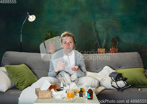 Image of Ill young girl with fever and cold looks suffering at home